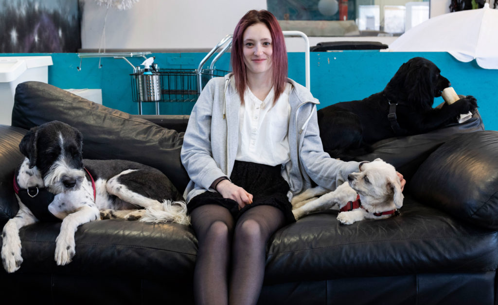 Hanna sitter i en soffa med två hundar